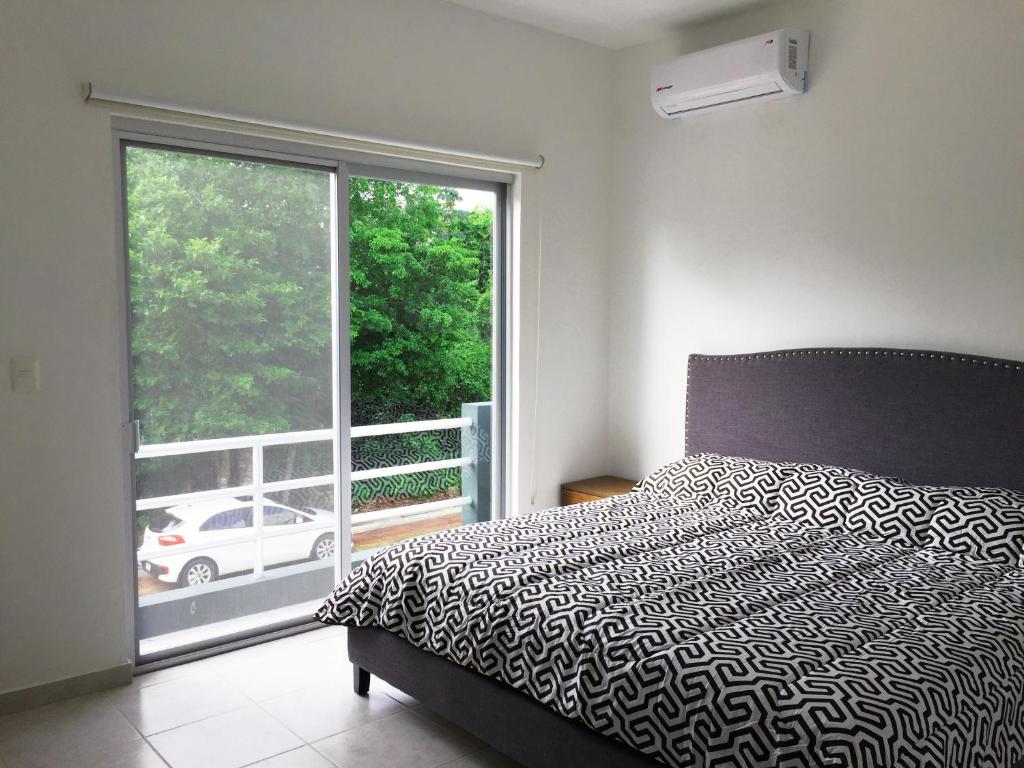 a bedroom with a bed and a large window at Hermosa Casa Vacacional Puerto Morelos in Puerto Morelos