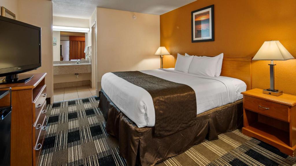 a hotel room with a bed and a flat screen tv at Best Western Tulsa Airport in East Tulsa