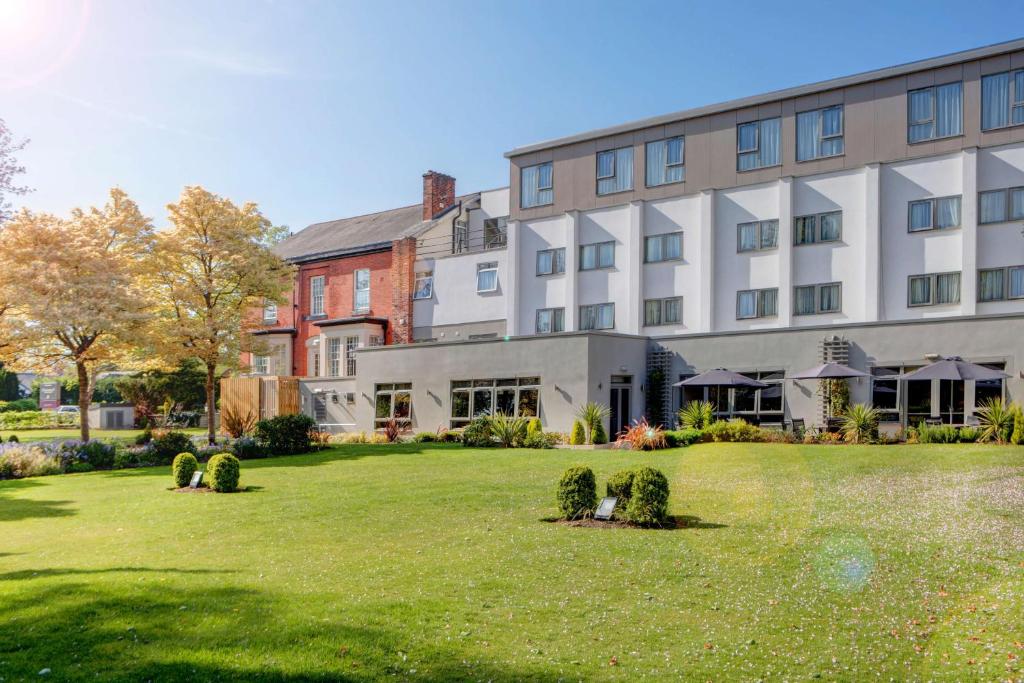 a large building with a lawn in front of it at Best Western Plus Pinewood Hotel, Manchester Airport South Handforth in Handforth
