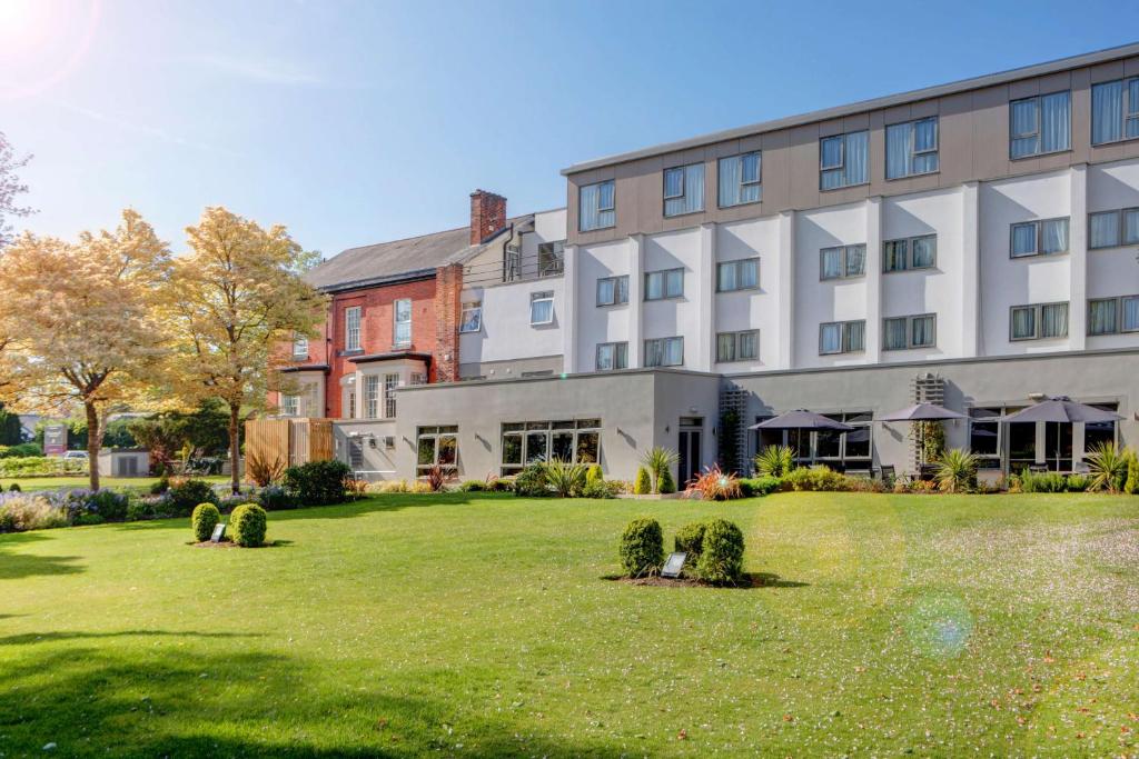 a large building with a lawn in front of it at Best Western Plus Pinewood Manchester Airport-Wilmslow Hotel in Handforth