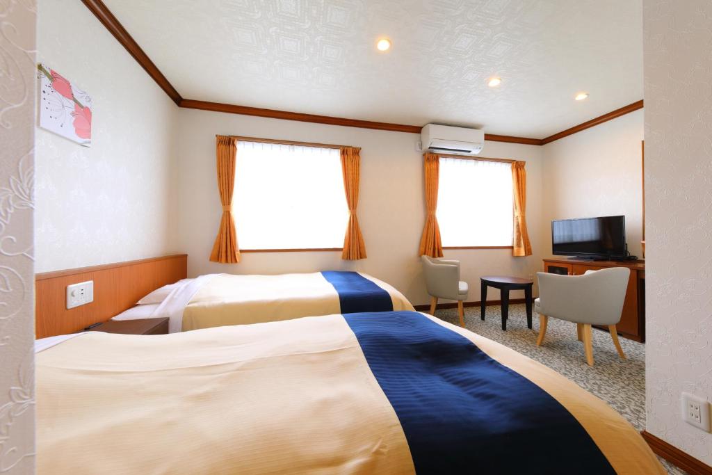 a hotel room with two beds and a tv at Business Hotel Star in Beppu