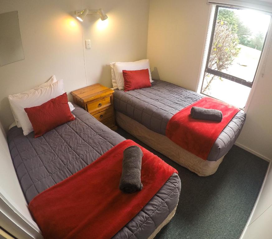 due letti in una piccola stanza con una finestra di Mt Aspiring Holiday Park a Wanaka