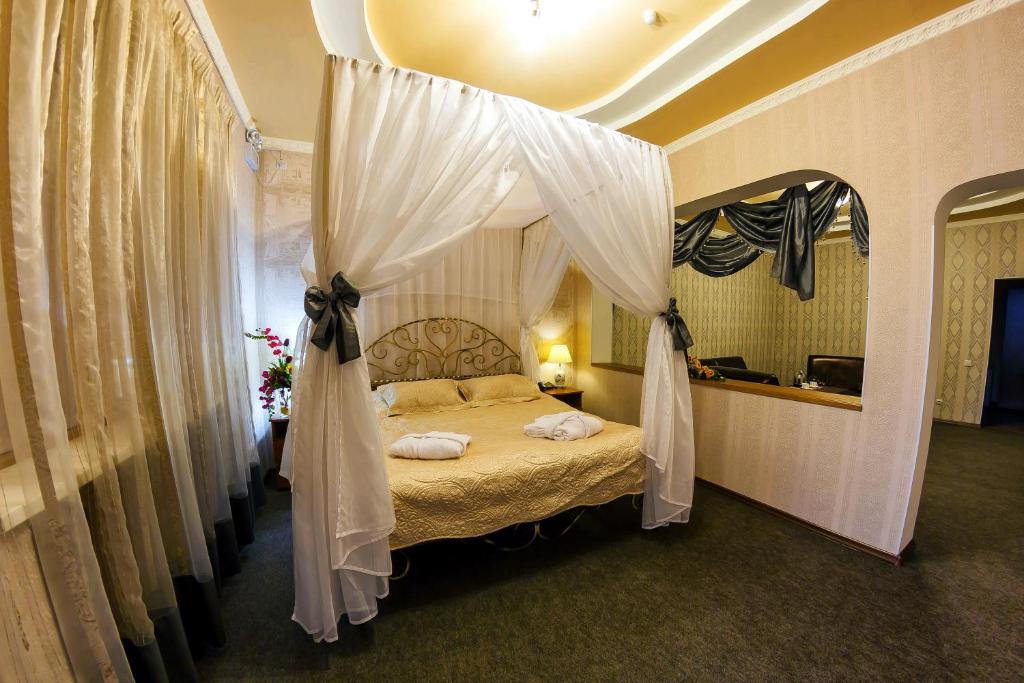 a bedroom with a canopy bed with white drapes at Ani Hotel in Khabarovsk