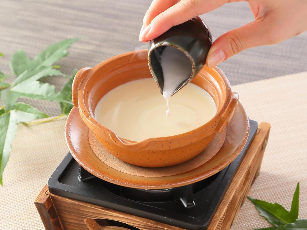 a person pouring milk into a cup of coffee at Hotel Binario Saga Arashiyama in Kyoto