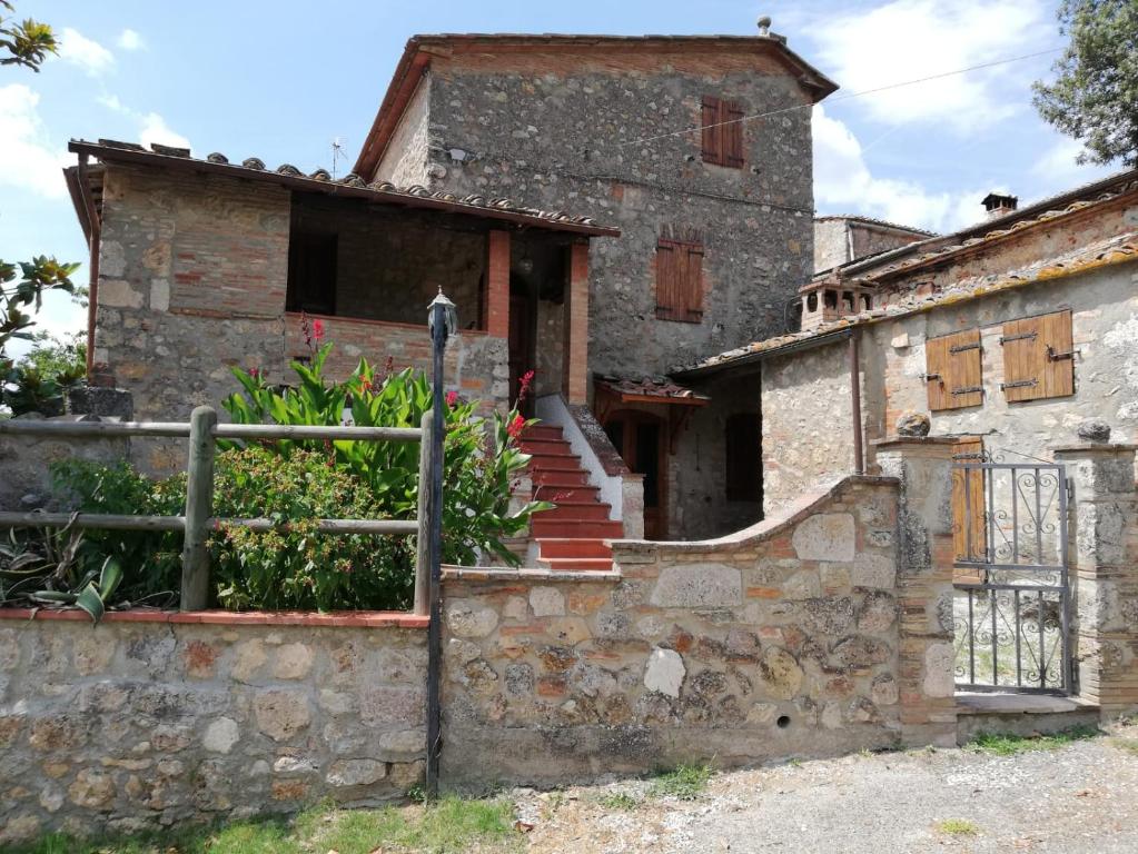 an old stone house with a staircase in front of it at IL Fienile nella Roccia in Casole dʼElsa