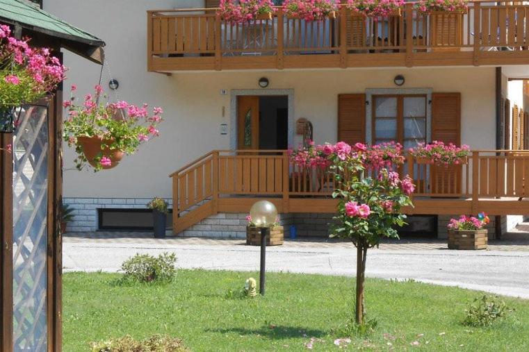 a house with a balcony with flowers in the yard at Casa Valentina in Ledro