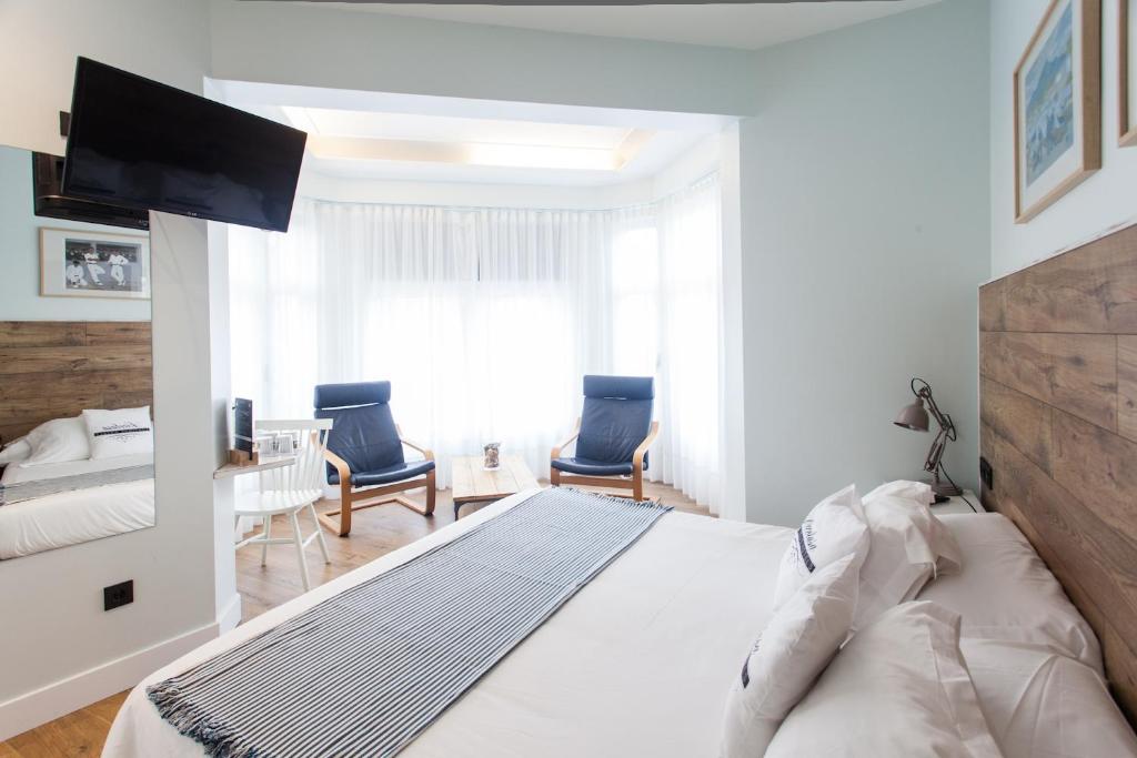 ein weißes Schlafzimmer mit einem großen Bett und 2 Stühlen in der Unterkunft Aldamar in San Sebastián