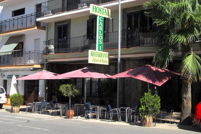 a restaurant with tables and umbrellas in front of a building at Hostal Carlos I in Herrera del Duque