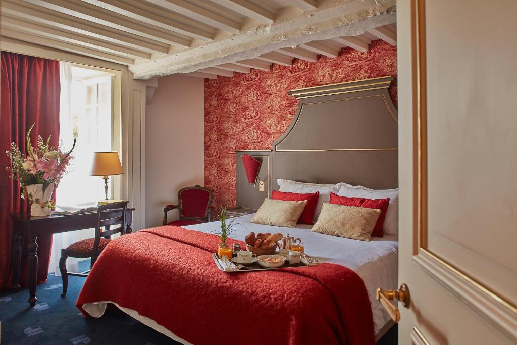 Cette chambre d'hôtel dispose d'un lit avec un mur rouge. dans l'établissement Chateau d'Audrieu, à Audrieu