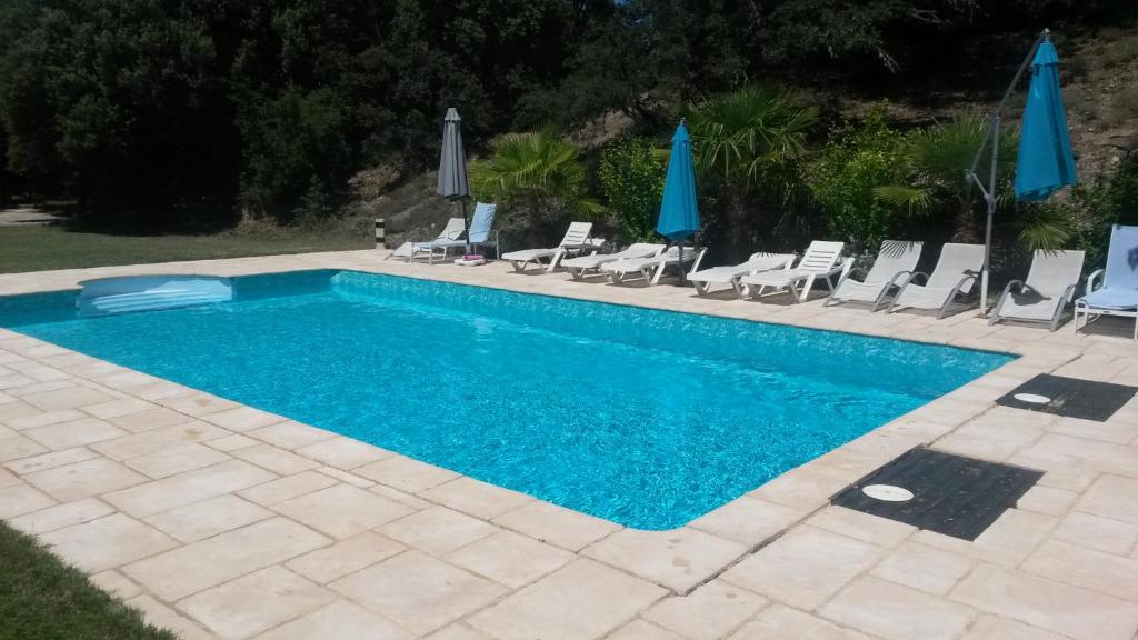 een zwembad met stoelen en parasols bij Ferme de Palumiane - Chambres climatisées in Visan