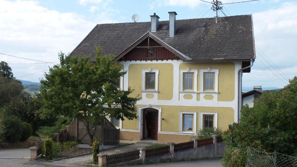una casa amarilla con techo negro en Hartl Apartments, en Kirchberg ob der Donau