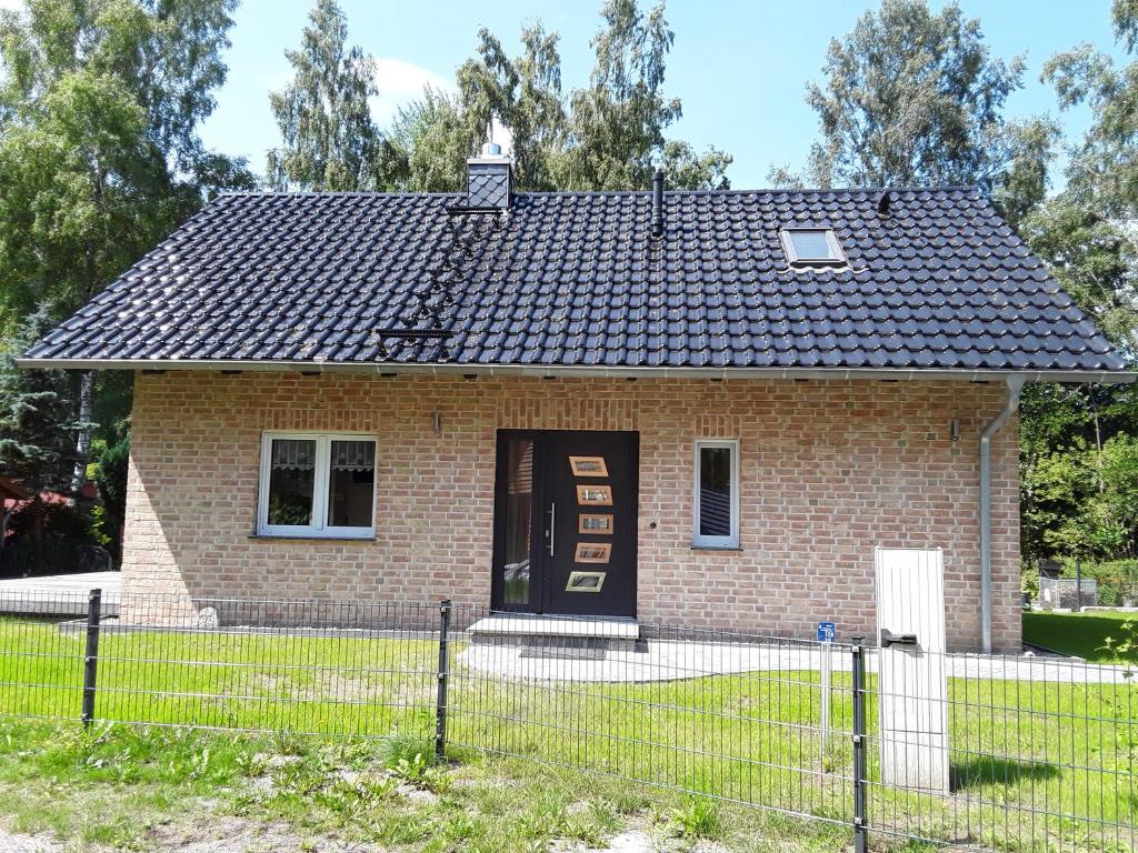 una pequeña casa de ladrillo con una puerta negra en Birkenhainring 34 en Trassenheide