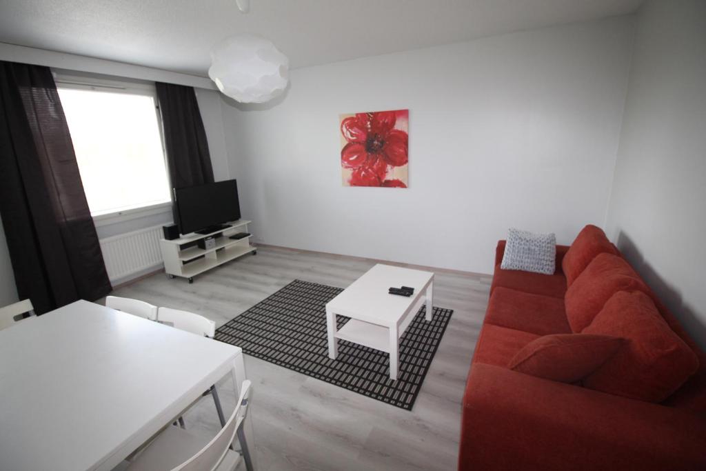 a living room with a red couch and a table at Apartment Kirkkokatu in Raahe