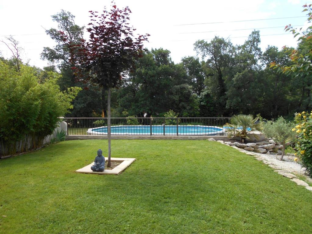 un jardin avec un arbre et une piscine dans l'établissement chez lulu, à Saint-Saturnin-lès-Apt