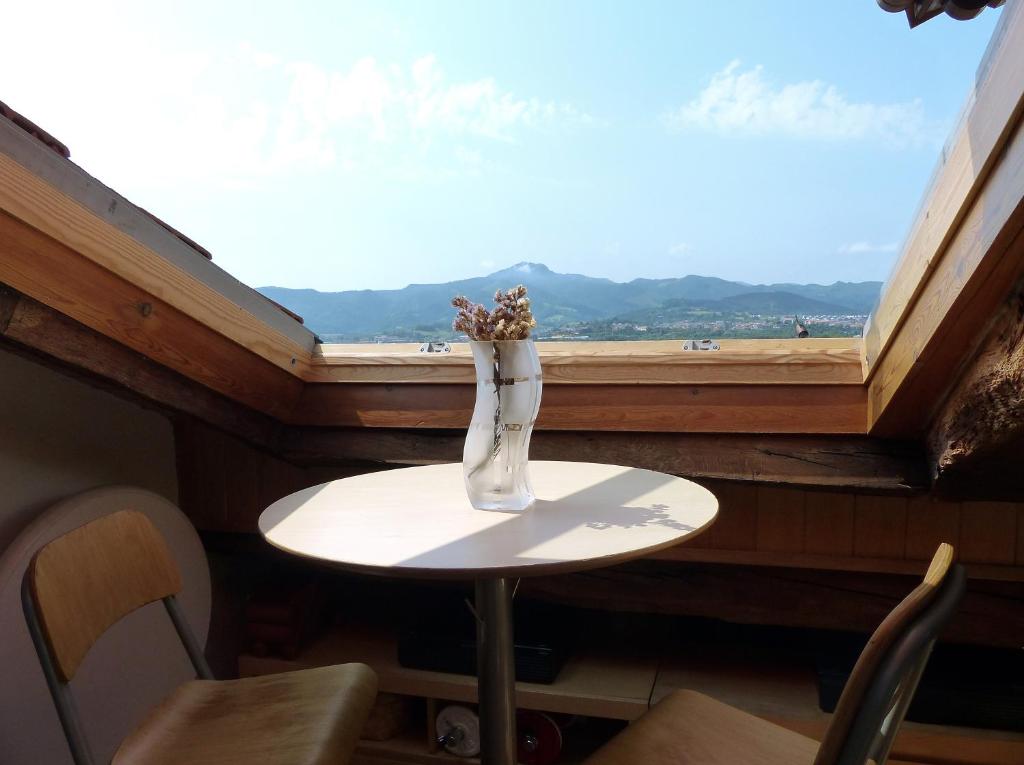 un jarrón de flores sentado en una mesa frente a una ventana en Handia - Basquenjoy, en Hondarribia