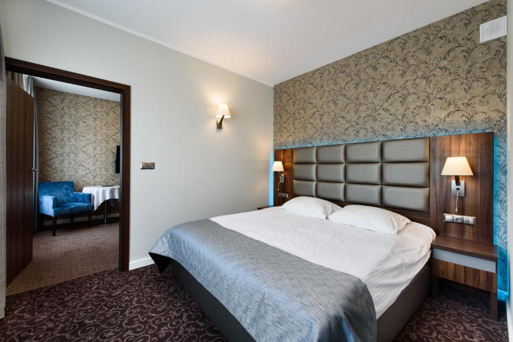a hotel room with a large bed and a chair at Hotel Nowy Dwór in Trzebnica