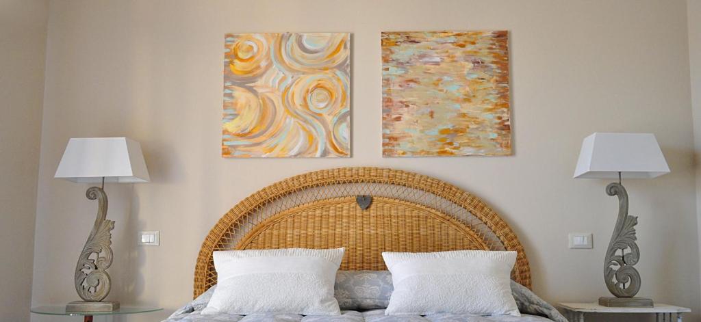 a bed with two lamps and two paintings on the wall at B&B Acquamarina in Marina di Massa