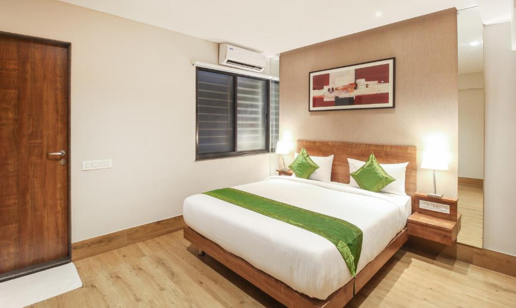 贝尔高姆Treebo Elite Residency Belgaum的卧室里有一张白色的大床，上面放着绿色的枕头