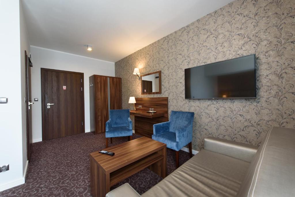 a hotel room with a desk and a television on the wall at Hotel Nowy Dwór in Trzebnica