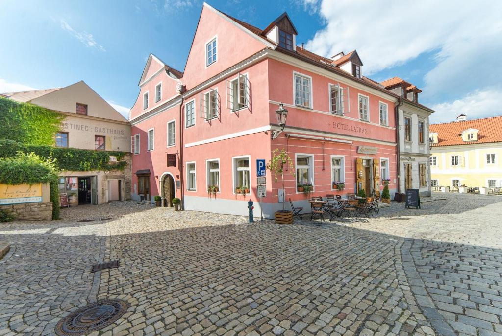 a large pink building on a cobblestone street at Hotel Latrán in Český Krumlov