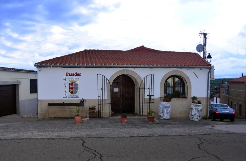 un pequeño edificio blanco con techo marrón en La pension del Parador, en Galisteo