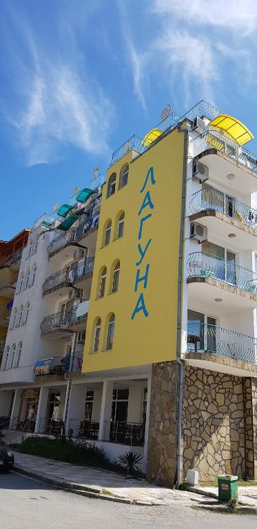 a yellow building with a sign on the side of it at Hotel Laguna - Guest House in Primorsko
