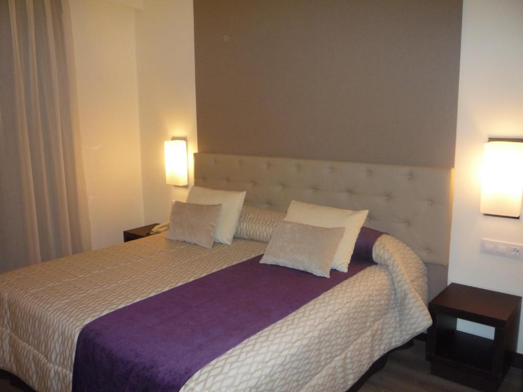a bedroom with a large bed with two pillows at Hotel Complejo París in Illescas