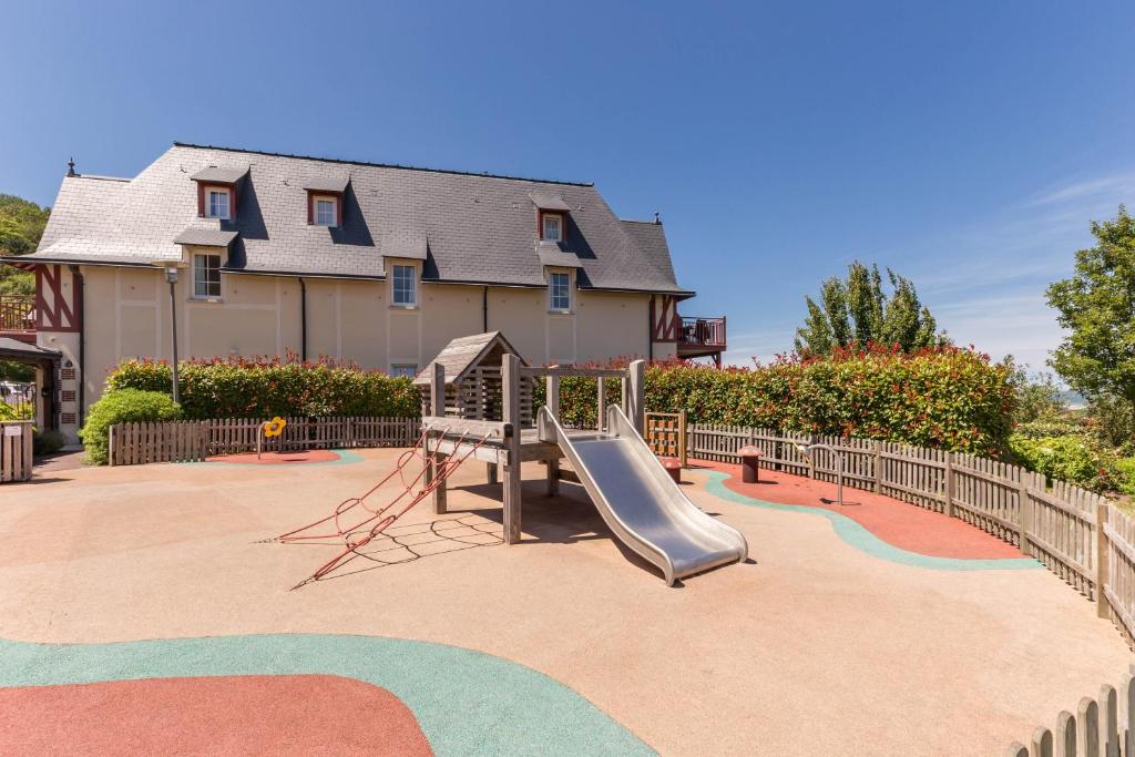 a playground with a slide in front of a house at Pierre & Vacances Premium Residence & Spa Houlgate in Houlgate