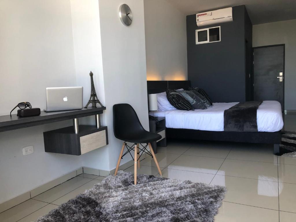 Schlafzimmer mit einem Bett und einem Schreibtisch mit einem Laptop in der Unterkunft Hotel Doral Inn in Ibagué
