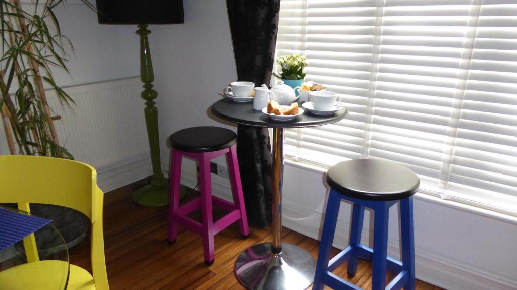 une table avec deux tabourets et une table avec de la nourriture dans l'établissement Bamboo Guesthouse, à Bournemouth