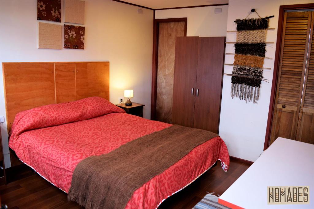 1 dormitorio con cama roja y armarios de madera en Nomades Chiloe Apart Hotel, en Castro