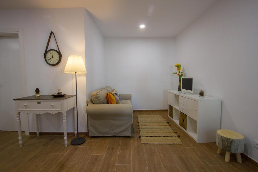 a living room with a chair and a desk and a clock at Casa dos Avós in Villa Nogueira