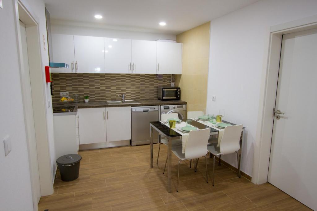 a kitchen with white cabinets and a table and chairs at Casa dos Avós in Villa Nogueira