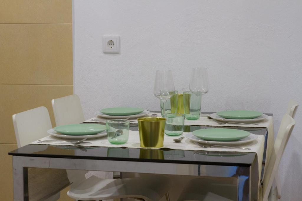 a table with green plates and glasses on it at Casa dos Avós in Villa Nogueira