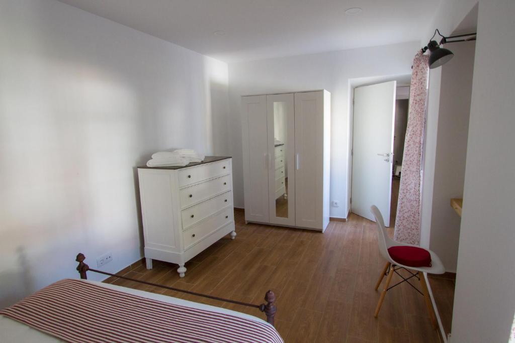 a bedroom with a bed and a dresser and a chair at Casa dos Avós in Villa Nogueira