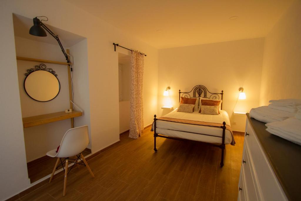 a bedroom with a bed and a mirror and a chair at Casa dos Avós in Villa Nogueira