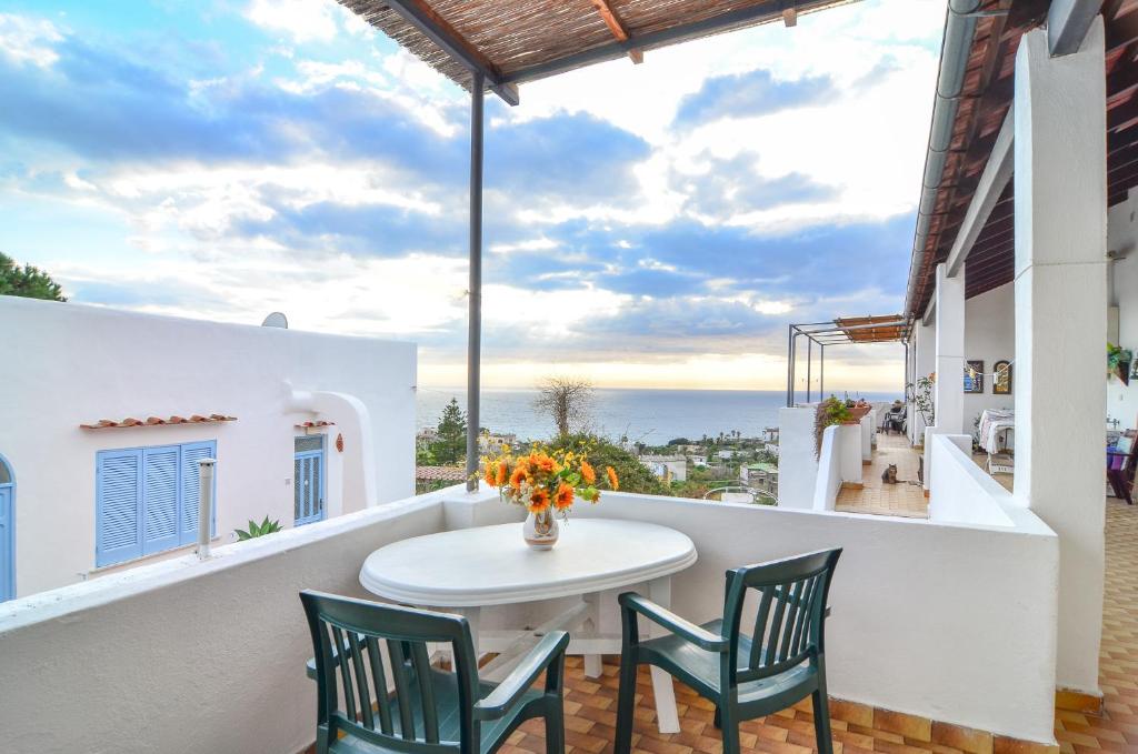 einen Balkon mit einem Tisch, Stühlen und Meerblick in der Unterkunft Residence Limoneto Ischia in Ischia