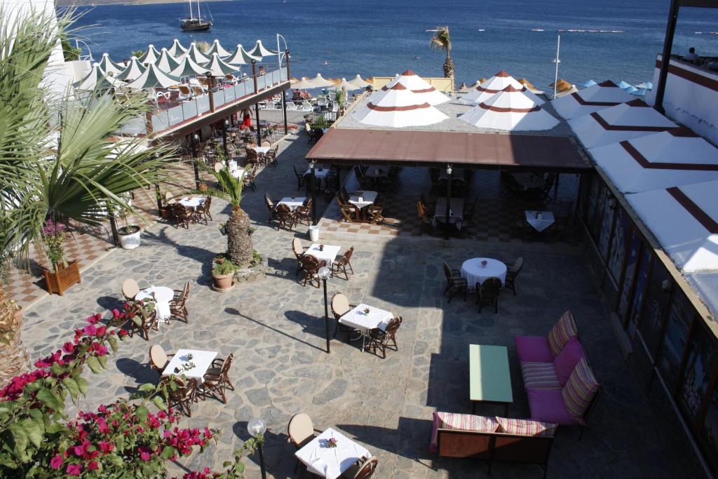 an outdoor patio with tables and chairs and the ocean at Amfora Hotel in Ortakent