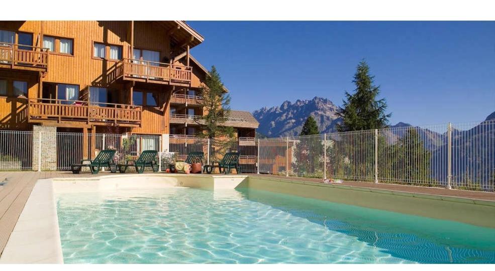 uma piscina em frente a um edifício de apartamentos em Le Hameau des Ecrins Station 1800 em Puy-Saint-Vincent