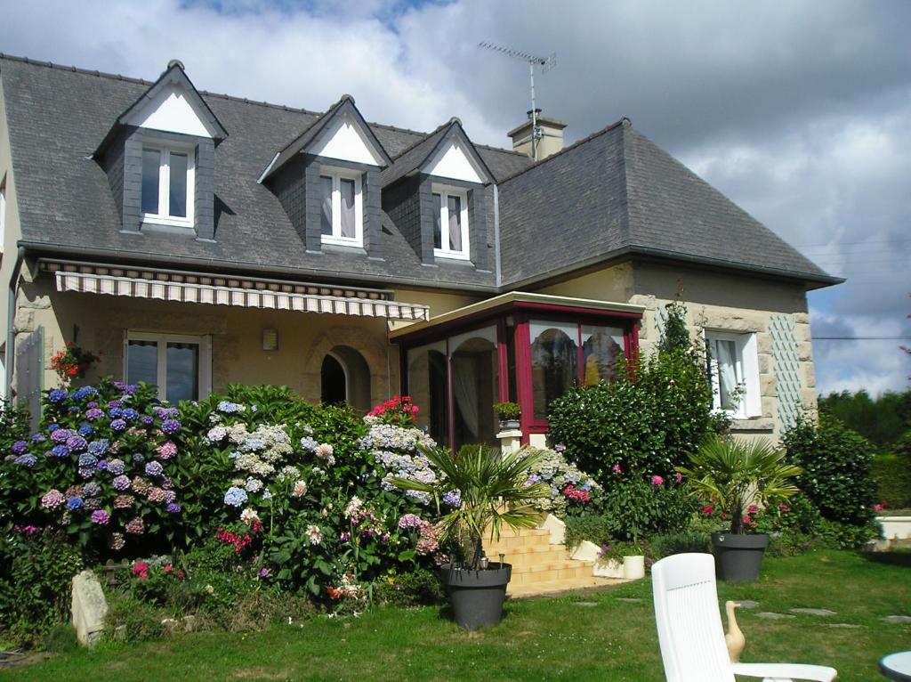 une maison avec des fleurs devant dans l'établissement Les Hortensias, à Saint-Pierre-de-Plesguen