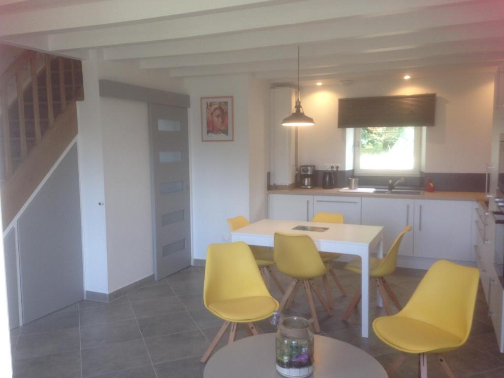 eine Küche und ein Esszimmer mit gelben Stühlen und einem Tisch in der Unterkunft Le puit du lavoir in Thiré
