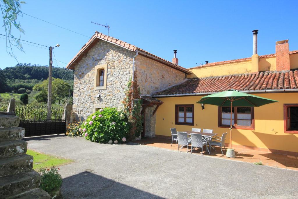 una casa con una mesa y una sombrilla verde en La Llosa II, en Villaviciosa