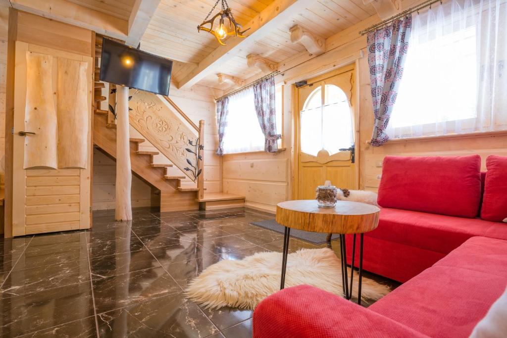 uma sala de estar com um sofá vermelho e uma mesa em Domki u Magdy em Zakopane