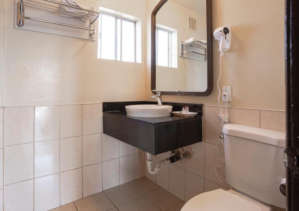 a bathroom with a sink and a toilet and a mirror at Value Inn Hollywood in Los Angeles