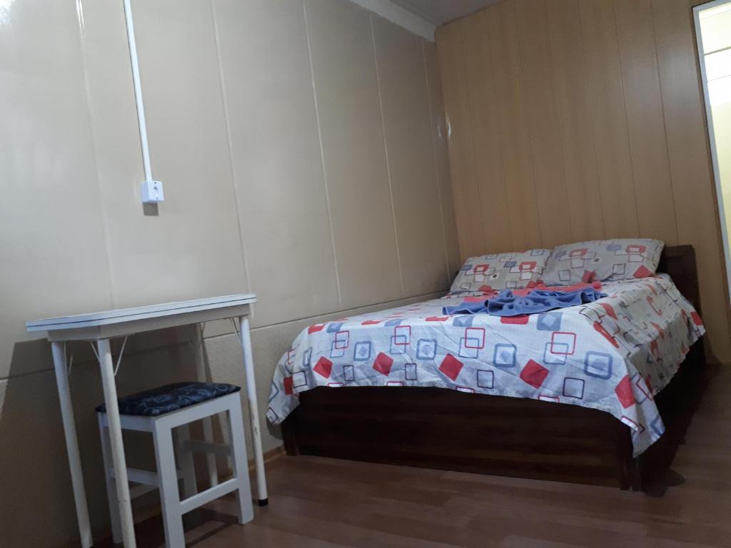 um pequeno quarto com uma cama e uma mesa em Suíte Barros em Navegantes