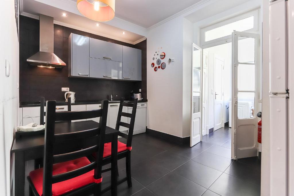 una cucina con mobili bianchi e neri e un tavolo di Lisbon Apartments in Anjos a Lisbona