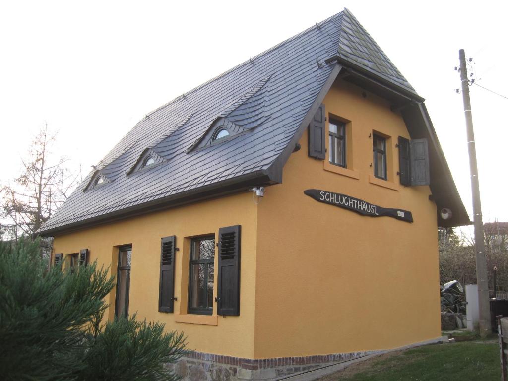 uma casa amarela com um telhado preto em Schluchthäusl em Lunzenau