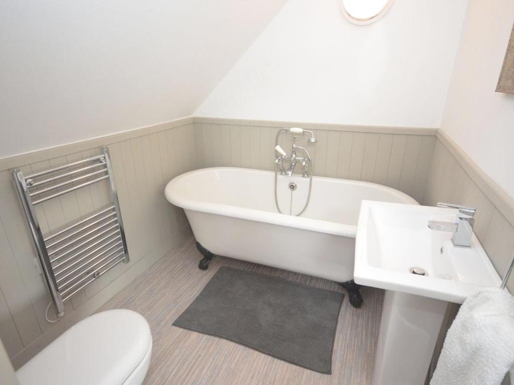 a bathroom with a tub and a toilet and a sink at Beach hut seaside cottage in Sheringham