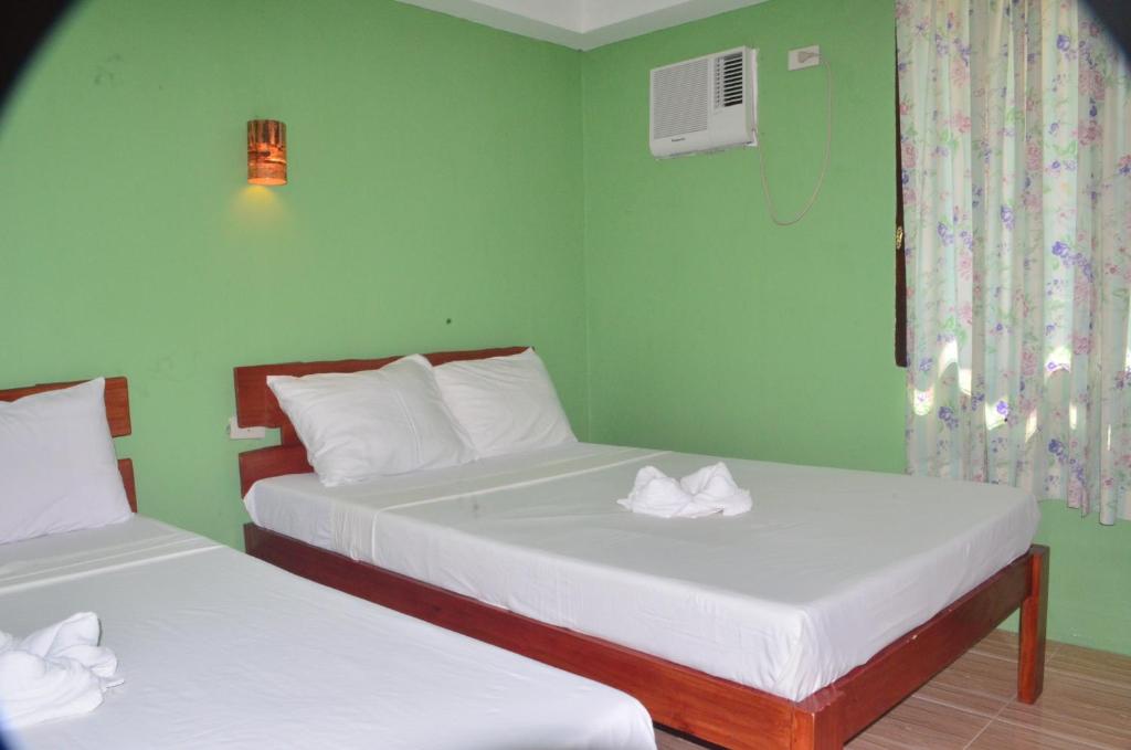 2 łóżka w pokoju z zielonymi ścianami w obiekcie Sf Cantina w mieście Wyspa Bantayan