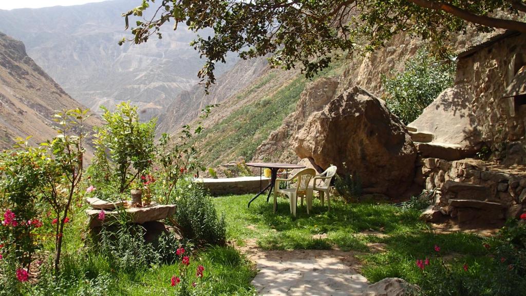 a table and chair in a garden with a view of a mountain at Casa De Virginia in Cabanaconde